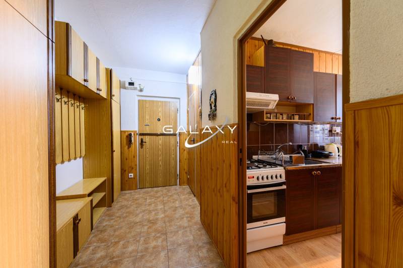 Der Flur und die Küche in einer Zweizimmerwohnung mit Holzdekor und Stauraum.