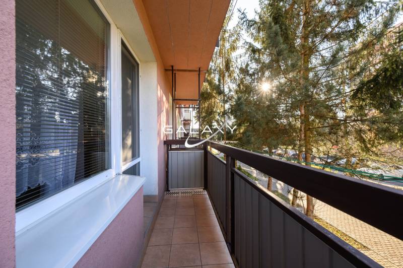 Ein Balkon in der Sládkovičova-Straße in Fiľakovo, umgeben von Grün, Teil einer 2-Zimmer-Wohnung.