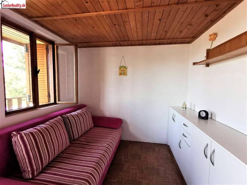 Eine Hütte mit einer Holzdecke, einem bequemen Sofa und weißen Aufbewahrungsmöbeln.