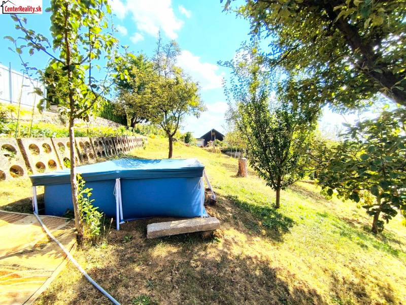 Auf dem Bild ist ein Garten mit einem Pool und einer Hütte, umgeben von Bäumen und Grünflächen.