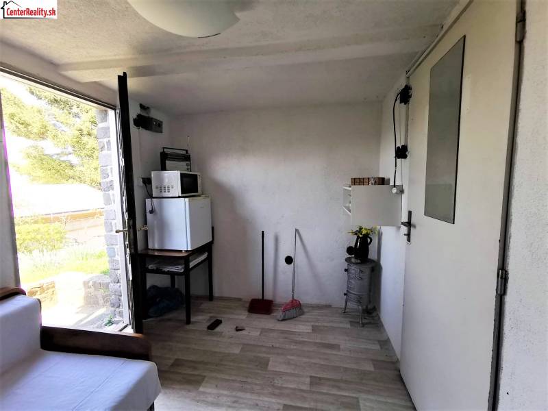 Interieur einer Hütte mit Geräten, Sofa und Blick auf die Natur draußen.