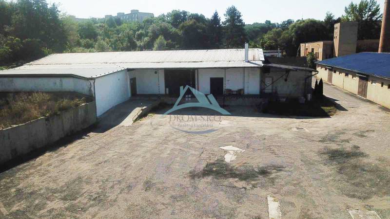 An der Straße Železničná befinden sich Lagerhallen, umgeben von Grünflächen, die zur Nutzung geeignet sind.