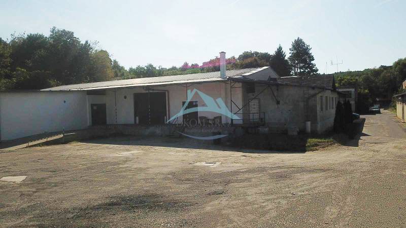 Lagerhäuser und Hallen in der Železničná-Straße in Veľký Krtíš, umgeben von Bäumen.