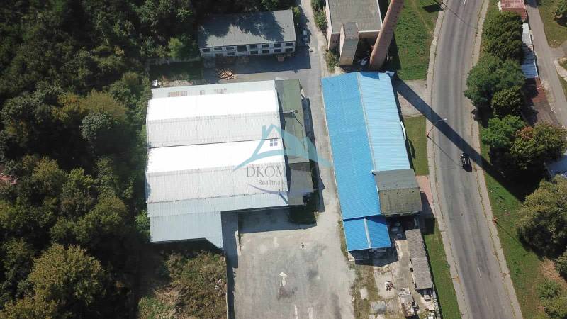 Luftaufnahme von Hallen und Lagern in der Nähe der Straße Železničná, umgeben von Grünflächen und Grundstücken.