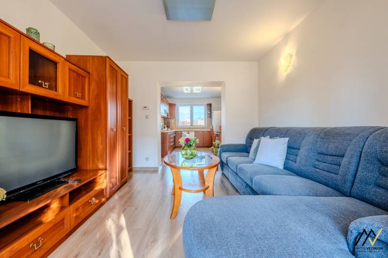 Wohnzimmer in einer Zweizimmerwohnung mit Holzboden und heller Küche.