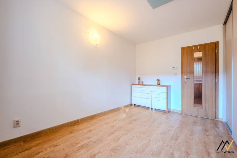 Ein Zimmer in einer 2-Zimmer-Wohnung mit einem Boden in Holzoptik und einer weißen Kommode.