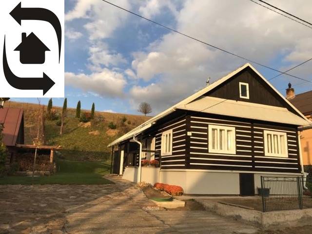 Eine Hütte in Legnava mit Holzverkleidung und gepflastertem Hof, umgeben von Natur und Hügeln.