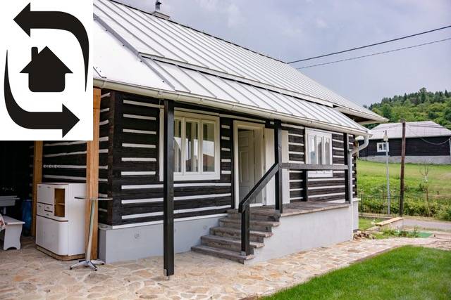 Ein Haus in Legnava mit einer Holzfassade und einer gepflasterten Terrasse, umgeben von Grün und Natur.