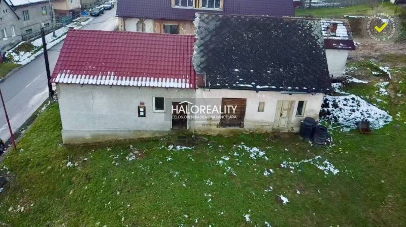 Ein älteres Familienhaus in Klenovec mit einem schrägen Dach auf einem verschneiten Grundstück.