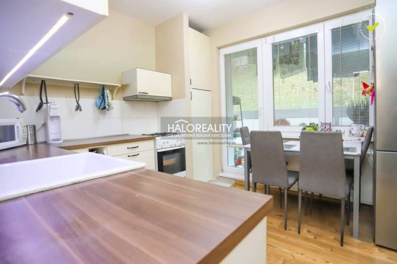 Küche in einer 2-Zimmer-Wohnung mit Holzboden, Esstisch und Geräten.