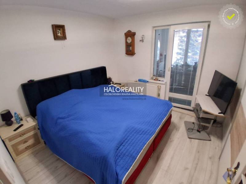 Schlafzimmer mit Bett, Fernseher, Holzboden und Balkontüren in einem Einfamilienhaus.