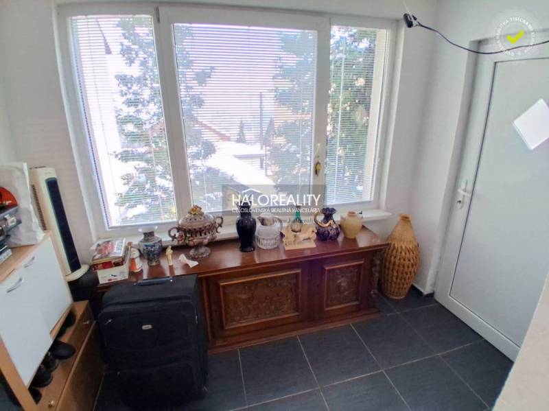 Ein Zimmer mit einem großen Fenster, einer dekorativen Kommode und verschiedenen Gegenständen in einem Einfamilienhaus.