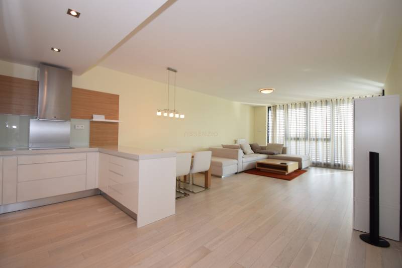 Wohnzimmer einer 3-Zimmer-Wohnung mit Holzboden, Kochnische und großen Fenstern.