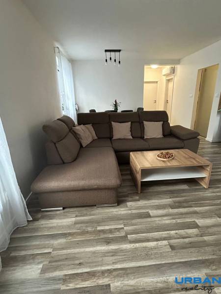 Gemütliches Wohnzimmer mit braunem Sofa und Tisch, Boden mit Holzdekor.