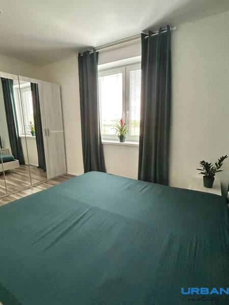 Schlafzimmer in einer 3-Zimmer-Wohnung mit einem Spiegelschrank, Vorhängen und einem Boden mit Holzdekor.