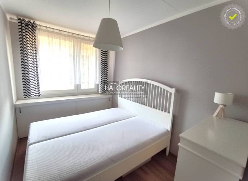 Schlafzimmer in einer 2-Zimmer-Wohnung mit weißen Möbeln und zarten Vorhängen.