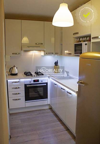 Küche in einer 2-Zimmer-Wohnung mit weißen Schränken und einem Boden in Holzoptik.