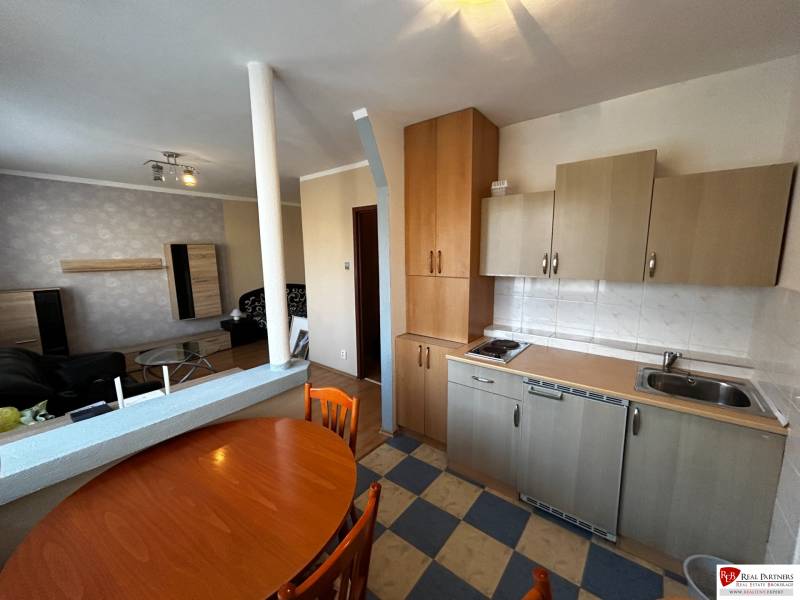 Küche mit Esstisch in einer Einzimmerwohnung, Boden mit Holzdekor.