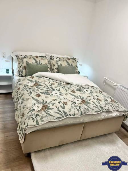 Schlafzimmer in einer 2-Zimmer-Wohnung mit Blumenbettwäsche und Holzboden.