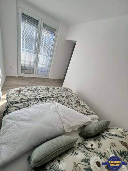 Helles Schlafzimmer in einer 2-Zimmer-Wohnung mit dekorativen Kissen und Holzboden.