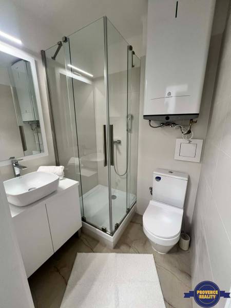 Badezimmer in einer 2-Zimmer-Wohnung mit moderner Duschkabine und Waschbecken.