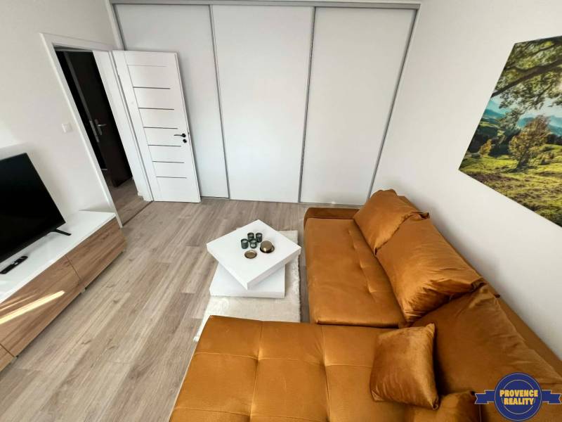 Wohnzimmer in einer Zweizimmerwohnung mit Holzboden und einem orangefarbenen Sofa.