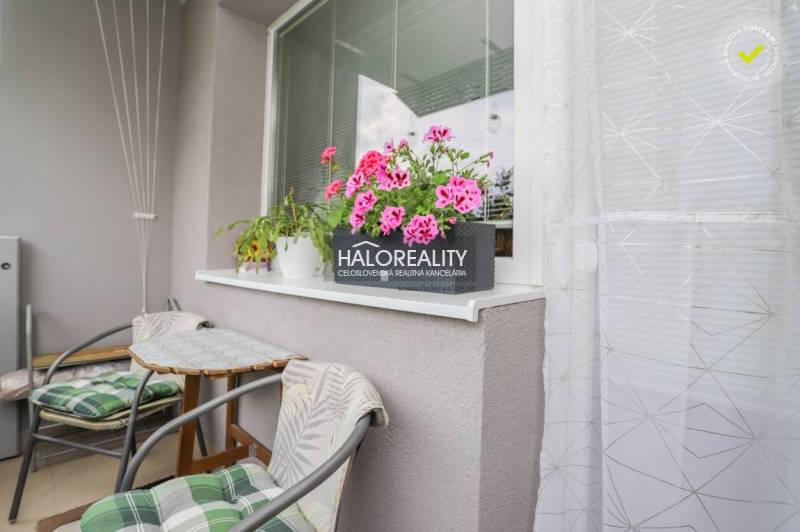 Ein Balkon einer 3-Zimmer-Wohnung mit Blumen und einem Tisch, geeignet zum Entspannen.