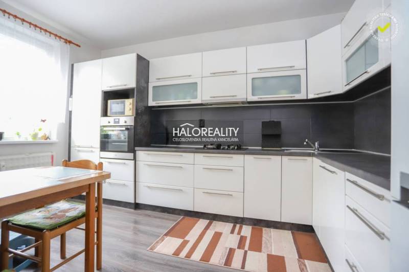 Küche in einer 3-Zimmer-Wohnung mit weißen Schränken und einem Boden in Holzoptik.