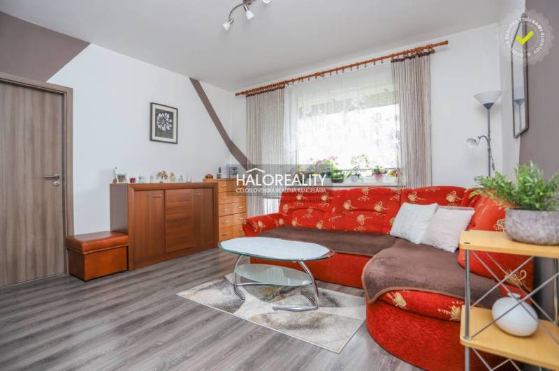 Wohnzimmer in einer 3-Zimmer-Wohnung mit rotem Sofa und Holzboden.