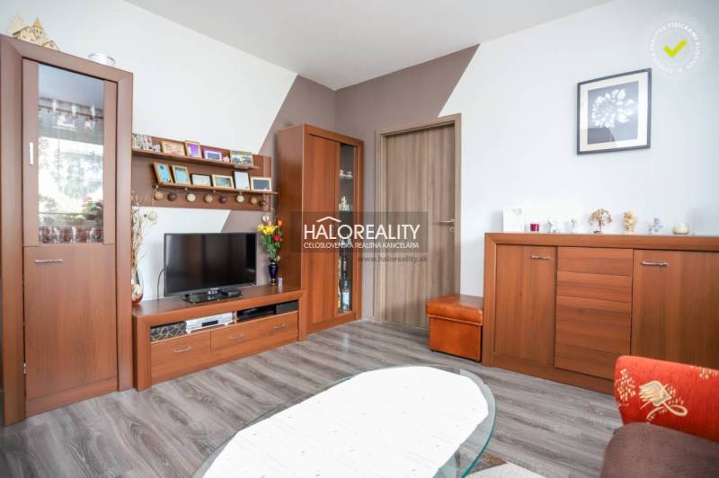 Wohnzimmer in einer 3-Zimmer-Wohnung mit Holzboden, Holzmöbeln und Fernseher.