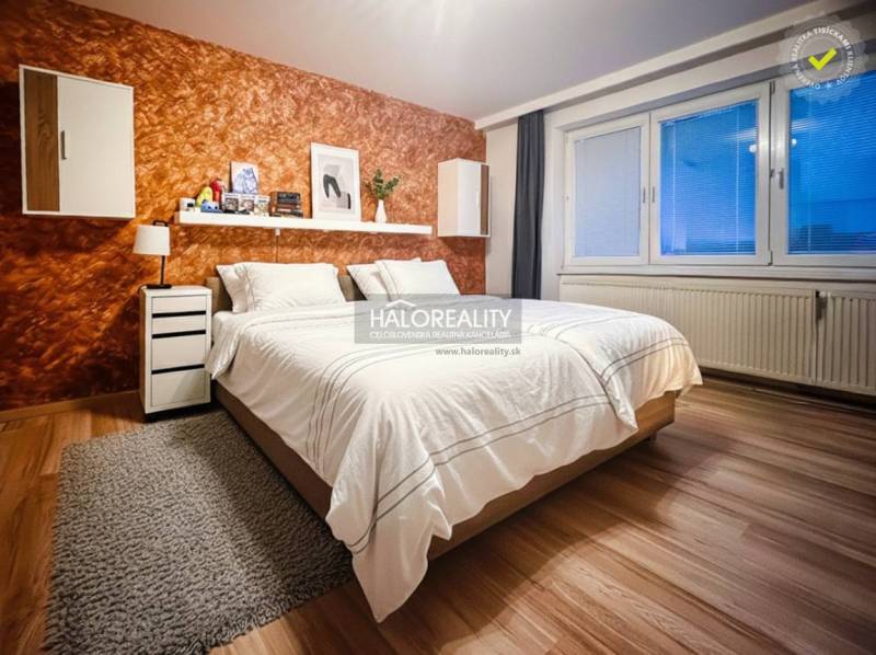 Schlafzimmer in einer 2-Zimmer-Wohnung mit Holzboden und einer orangefarbenen Wand.