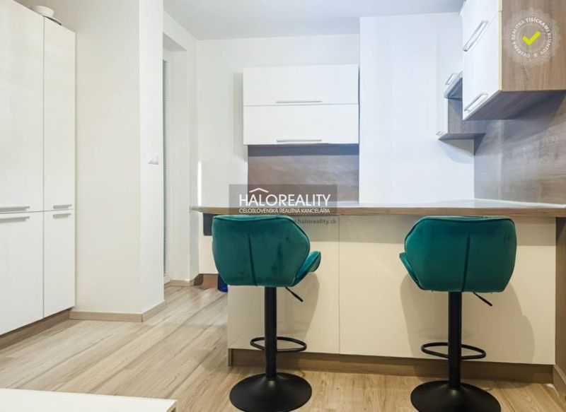 Küche in einer 2-Zimmer-Wohnung mit türkisfarbenen Stühlen und Holzboden.