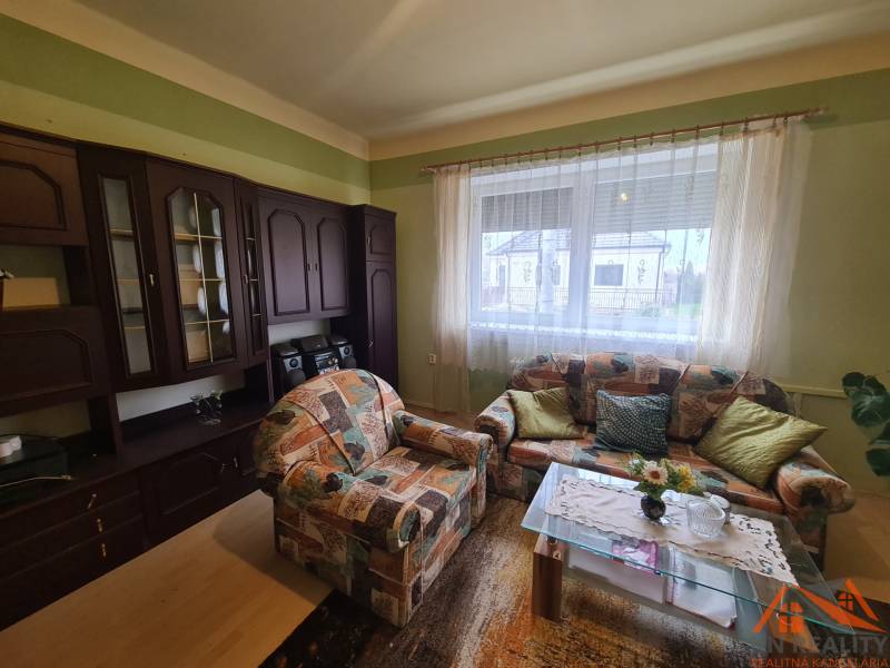 Wohnzimmer eines Einfamilienhauses mit einem bunten Sofa und einer dunklen Wohnwand.