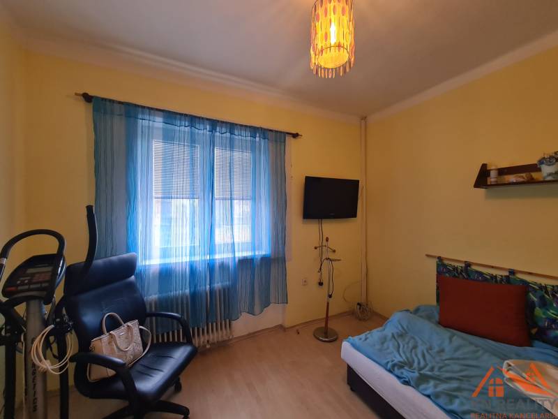 Ein Zimmer in einem Einfamilienhaus mit Fitnessgeräten, einem Sessel und einem Fernseher.