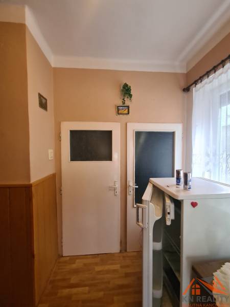 Innenraum eines Einfamilienhauses mit zwei Türen, einem Kühlschrank und einem Boden mit Holzdekor.