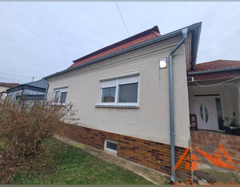 Ein Einfamilienhaus in Hurbanovo mit heller Fassade und rotem Dach, umgeben von Sträuchern.