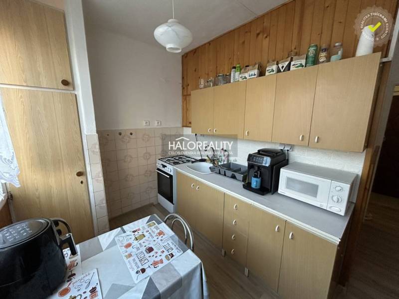 Küche in einer 2-Zimmer-Wohnung mit Holzdekor, einschließlich Geräten und Esstisch.