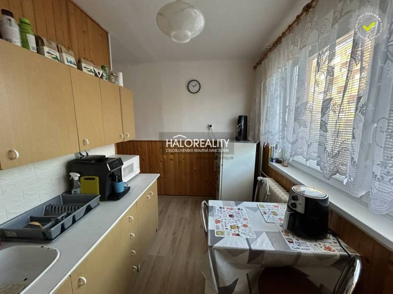 Küche in einer 2-Zimmer-Wohnung mit Geräten und langen Vorhängen am Fenster.