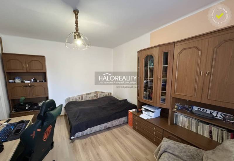 Schlafzimmer in einer 2-Zimmer-Wohnung mit Holzboden und einer Möbelwand aus Holz.