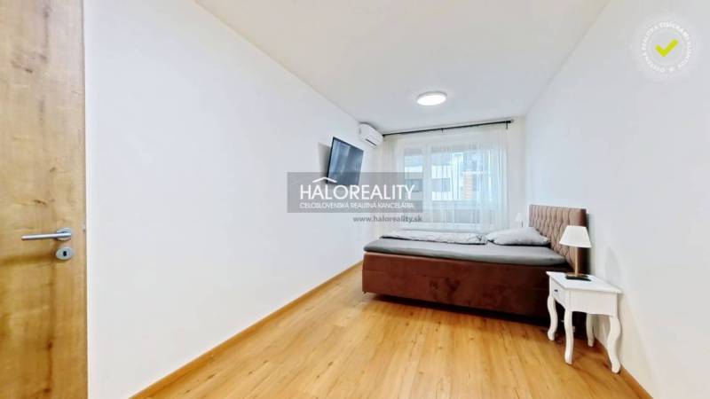 Schlafzimmer in einer 2-Zimmer-Wohnung mit Bett, Nachttisch und Fernseher, hat einen Boden mit Holzdekor.