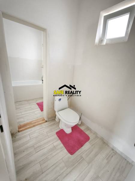 Badezimmer im Einfamilienhaus mit Toilette, Badewanne und Boden mit Holzdekor.