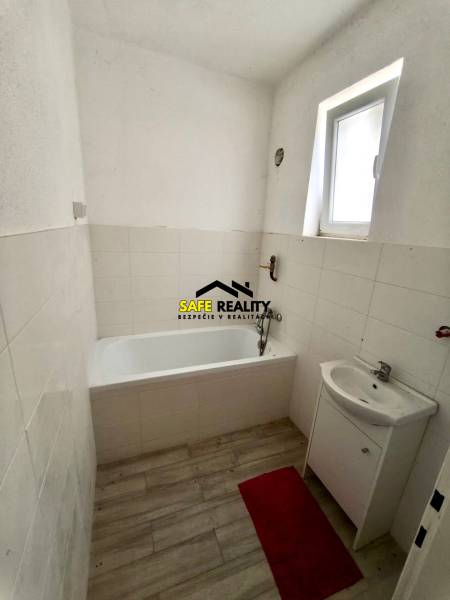 Badezimmer in einem Einfamilienhaus mit Badewanne, Waschbecken und Boden mit Holzdekor.