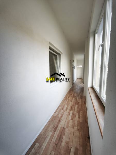 Ein Flur in einem Einfamilienhaus mit einem Boden in Holzoptik und großen Fenstern.