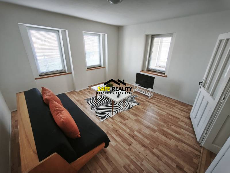 Wohnzimmer in einem Einfamilienhaus mit Sofa, Fernseher und Holzboden.