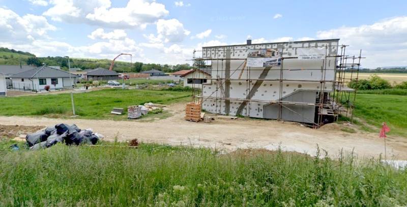 Baugrundstück zum Wohnen in Modrovka mit einem im Bau befindlichen Gebäude und Umgebung im Hintergrund.