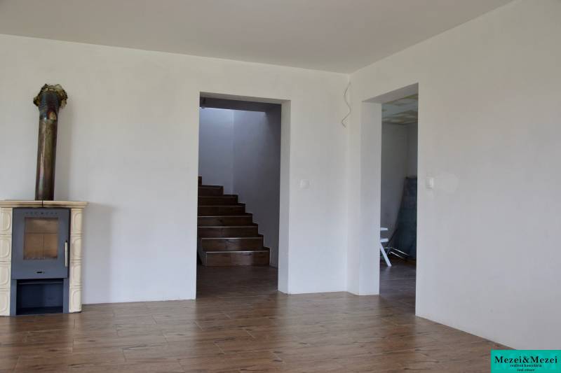 Innenraum eines Einfamilienhauses mit Kamin, Treppe und Boden in Holzoptik.