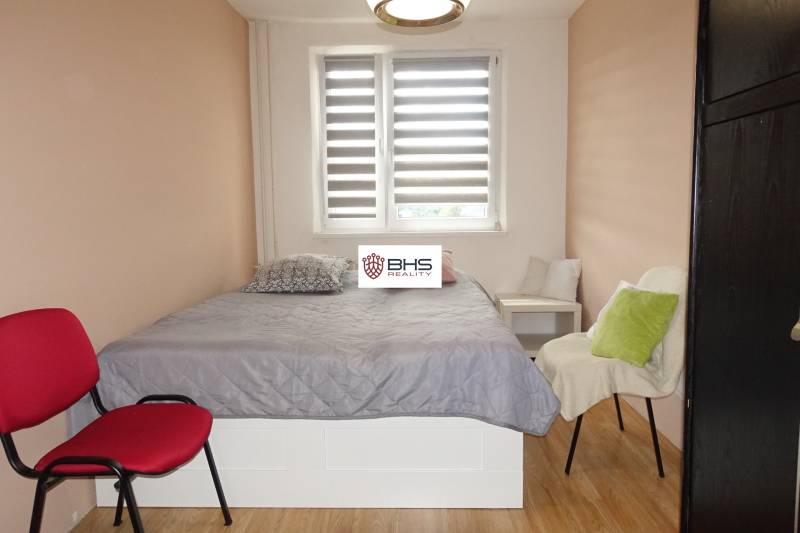 Schlafzimmer in einer 3-Zimmer-Wohnung mit Bett, Sesseln und Boden in Holzoptik.