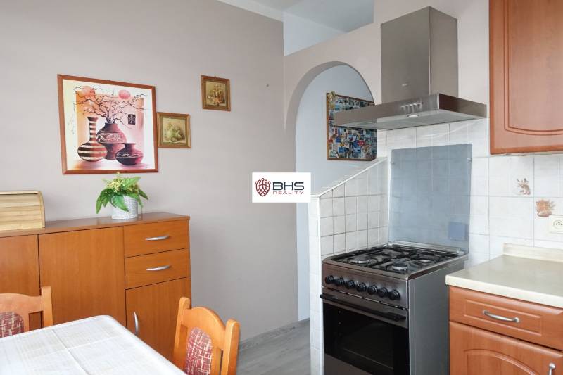 Küche in einer 3-Zimmer-Wohnung mit einem Gasherd und Holzmöbeldekor.