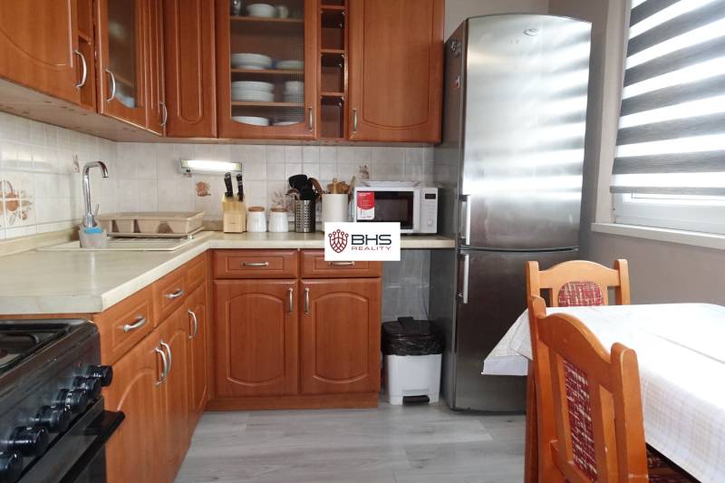 Küche mit Holzdekor, Herd, Kühlschrank und Esstisch in einer 3-Zimmer-Wohnung.