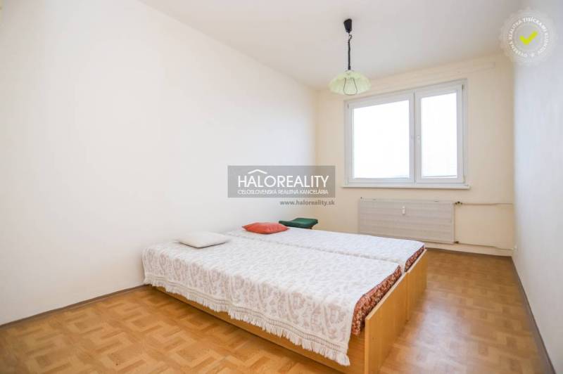 Schlafzimmer in einer 3-Zimmer-Wohnung mit Holzboden und einem Bett am Fenster.